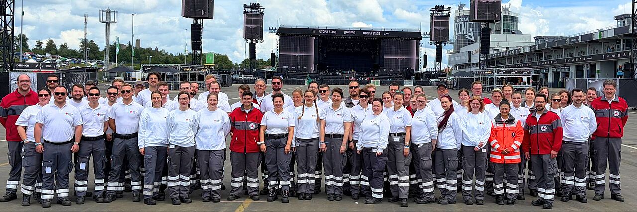 Gruppenfoto des DRK-OV Bad Neuenahr-Ahrweiler bei Rock am Ring. Das Team steht auf dem (noch) menschenleeren Infield.