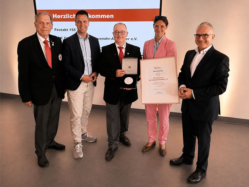 Gruppenfoto mit 5 Personen, Michael Assenmacher zeigt die Henry-Dunant-Plakette.